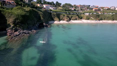 tiro de inclinación aérea de la playa pacífica agua esmeralda con edificios detrás