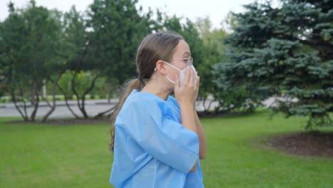 woman putting on her facemask and secures its tightness on her face while wearing lab coat, static