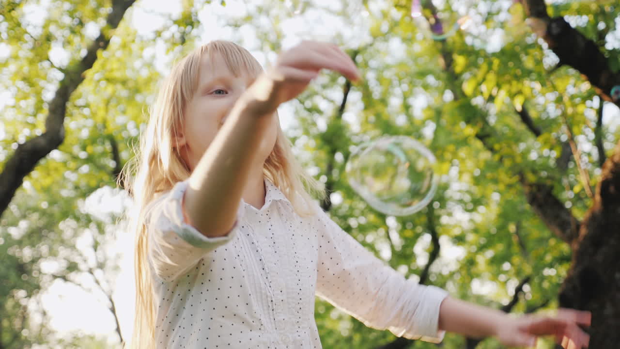 명랑한 금발 소녀가 비누 거품 평온한 행복한 유년기 개념 슬로우 모션 비디오를 가지고 놀고 있습니다