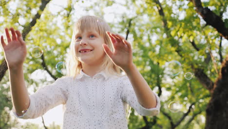 a cheerful blonde girl is playing with soap bubbles carefree happy childhood concept slow motion vid