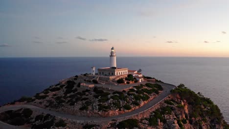 lighthouse on a cliff at the edge of the ocean blesses light signals at sunset