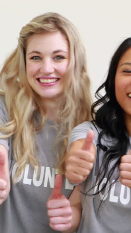 happy female volunteers showing thumbs up