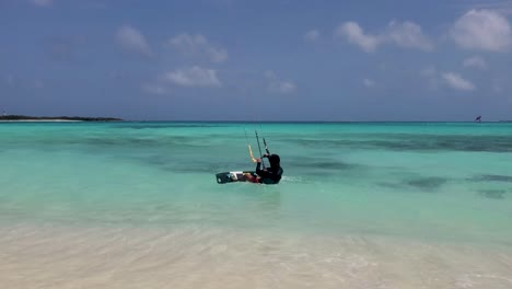 man lying on shallow water put kite board and start to fly kitesurf, slow motion