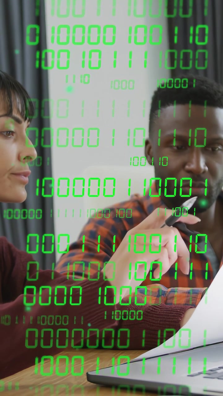 Vertical video: Man gesturing woman reading docs on laptop, binary code overlaying for tech review