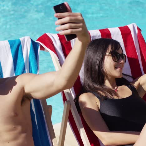 Man-and-woman-taking-self-portraits-at-pool