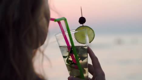 una mujer bebiendo mojito con una pajita.