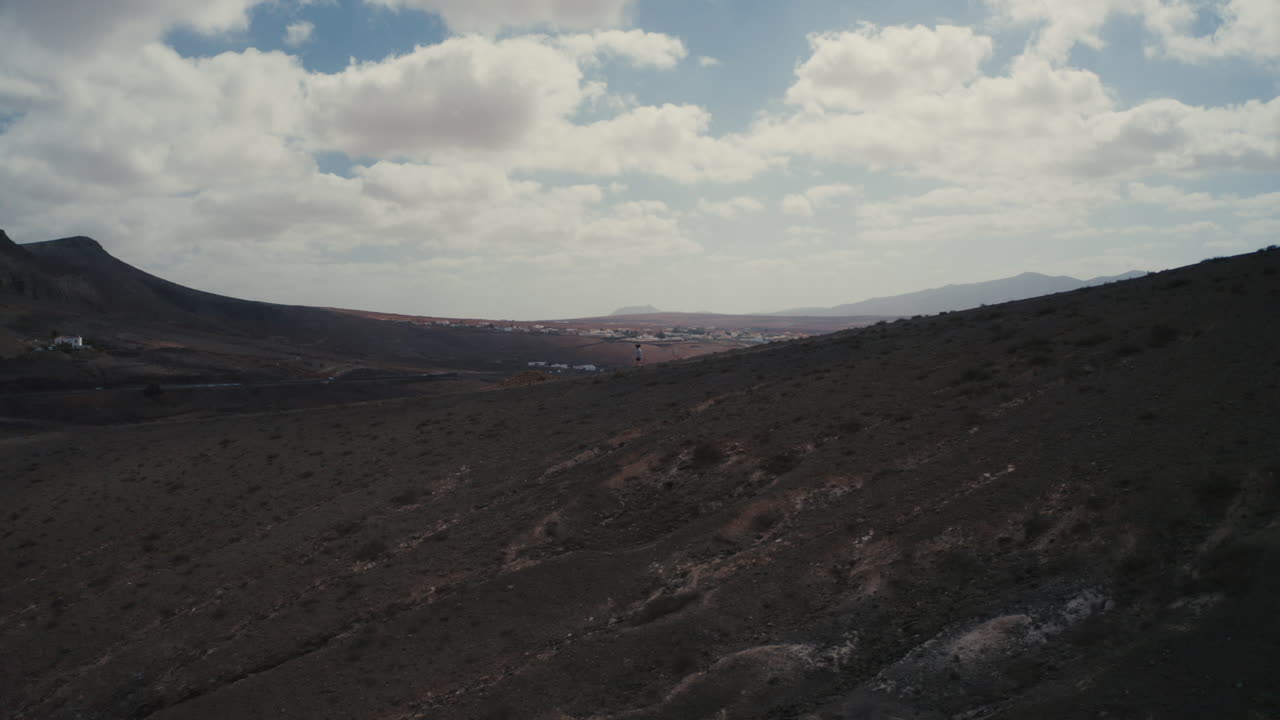 tiro de drone de una niña caminando en una montaña en fuerteventura