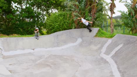 Front-view-of-young-caucasian-man-practicing-skateboarding-on-ramp-in-skateboard-park-4k