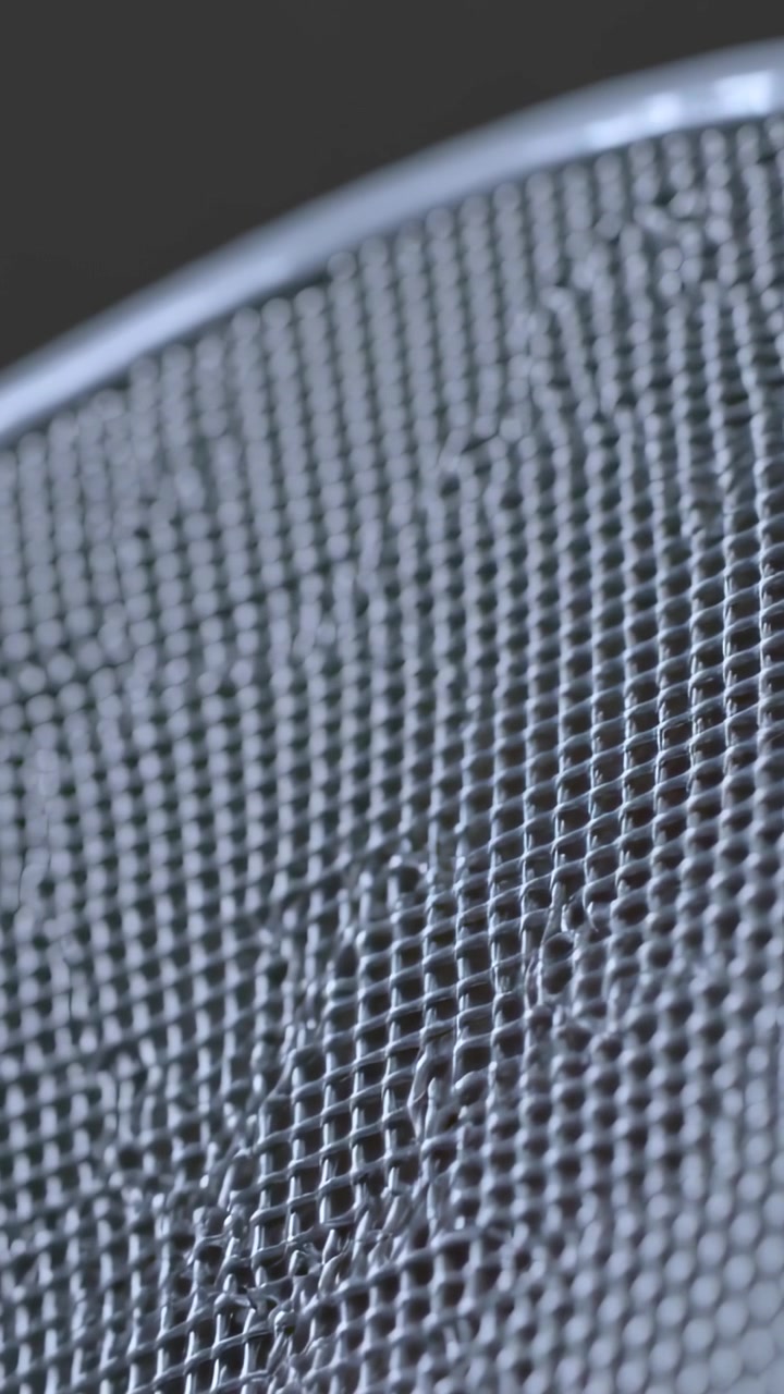 Vertical video: Shifting camera showing curved woven metal mesh rim in studio revealing droplets