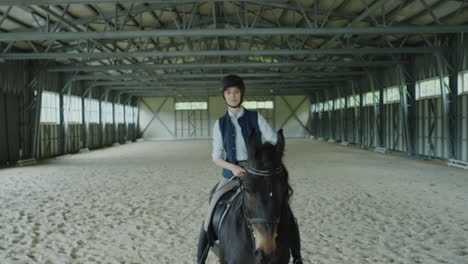 a person riding a horse in an indoor equestrian arena
