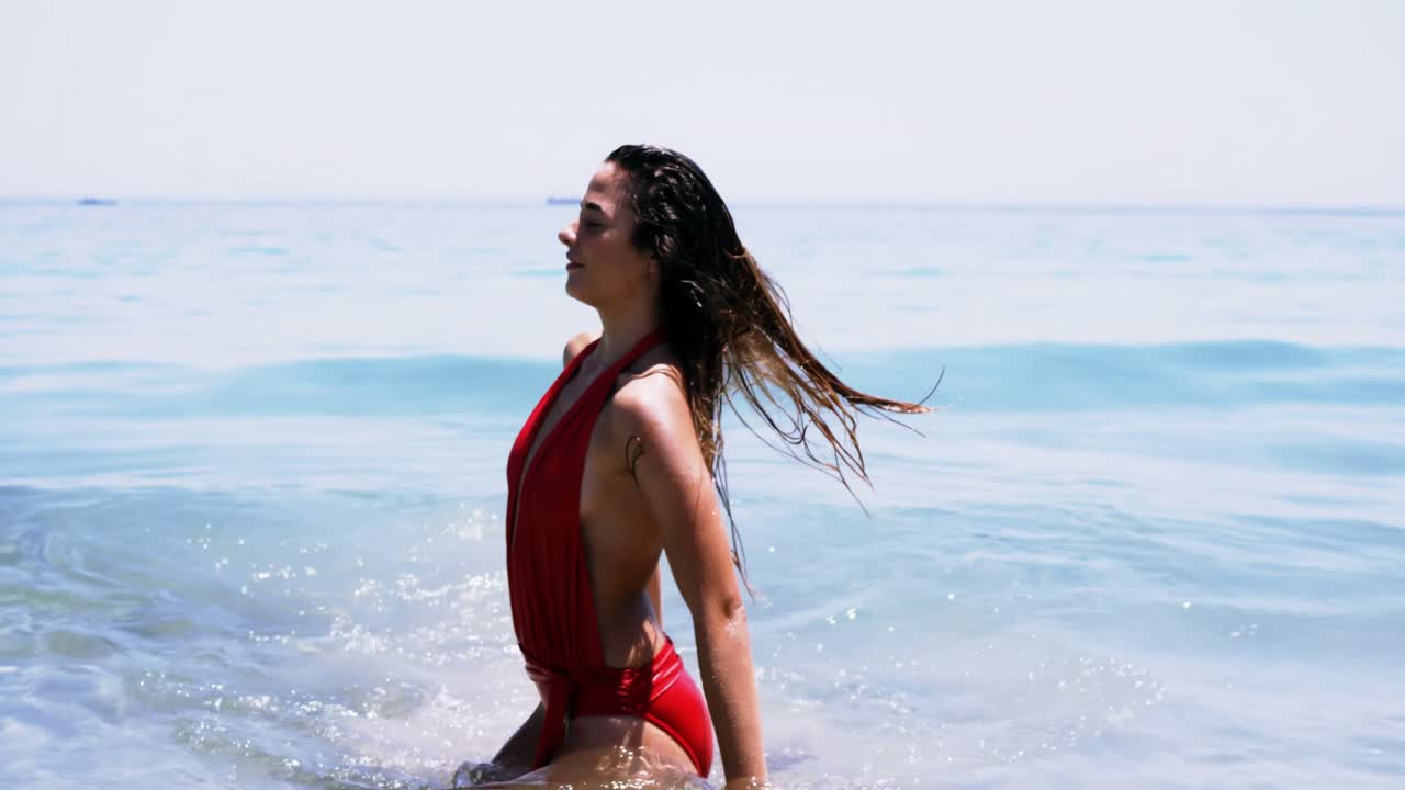 아름다운 여자가 해변에서 공중에 머리카락을 던지고 있습니다.