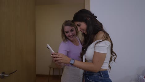two young women happily looking at a smartphone together