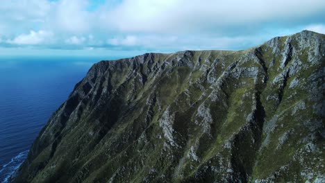 Toma-De-Drones-De-Las-Gigantescas-Montañas-Hoddevik-En-Noruega-Durante-El-Místico-Día-De-Niebla-Con-El-Mar-Azul-Como-Telón-De-Fondo