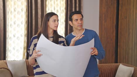 una pareja india recién casada discutiendo el plan de la casa.