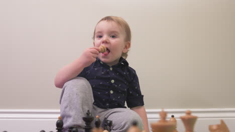 curious toddler boy puts a chess piece in his mouth