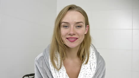 casual woman in bathrobe smiling to camera