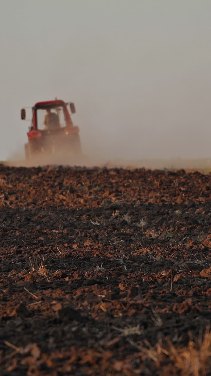 Tractor ploughing a field. Scale farming with tractor and plow in field Vertical video