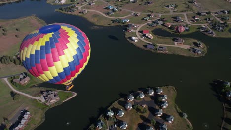 paracaídas de globo aerostático volando sobre el lago y las casas, campo de colorado, ee.uu.