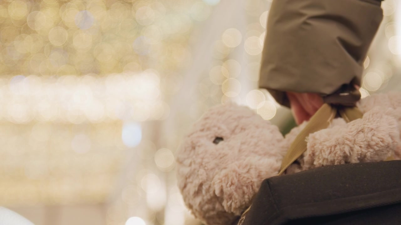 Bambino che stringe un giocattolo vicino al calore. Atmosfera celebrativa con luci scintillanti e tenero abbraccio. Scena festiva con bambino che tiene un orsetto di peluche tra decorazioni scintillanti e un'atmosfera accogliente
