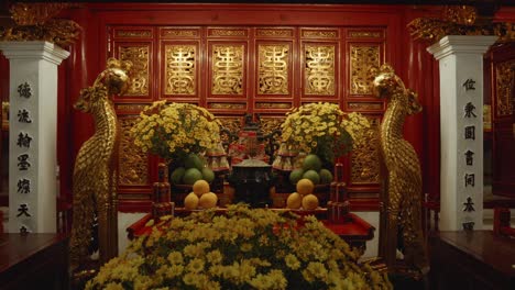 Inside-the-Ngoc-Son-Temple-in-Hanoi,-Vietnam,-an-ornate-altar-adorned-with-flowers-and-fruits-stands-in-the-center,-radiating-a-serene-and-spiritual-energy