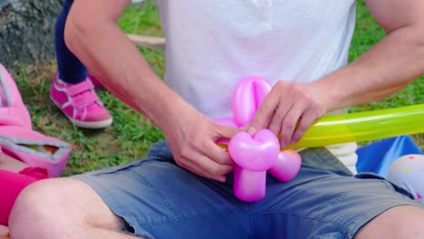 joven y lindo hombre europeo caucásico infla un globo en el fondo del parque