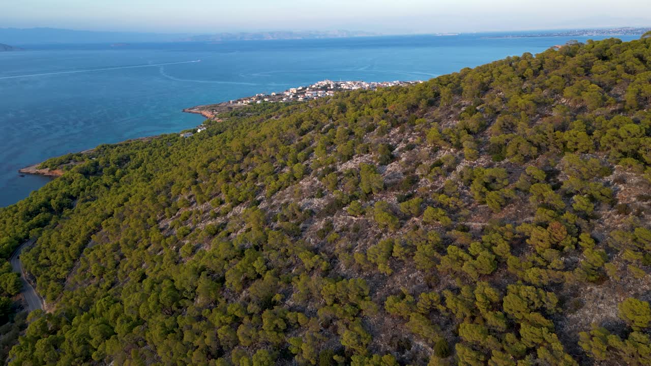 Drone reveal of Agistri village from behind hill with ocean in distance