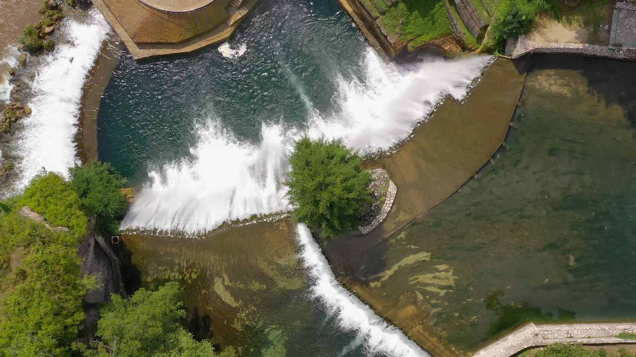 Jajce Waterfall in Bosnia and Herzegovina from above with large tree in between, Aerial top view close in shot