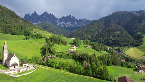 aerial backwards over chiesa di santa maddalena and odle mountain range in background