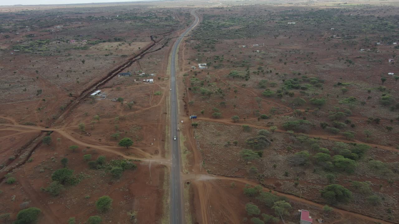 Autostrada che attraversa campi agricoli africani aridi, campagna nel Kenya meridionale, vista aerea.