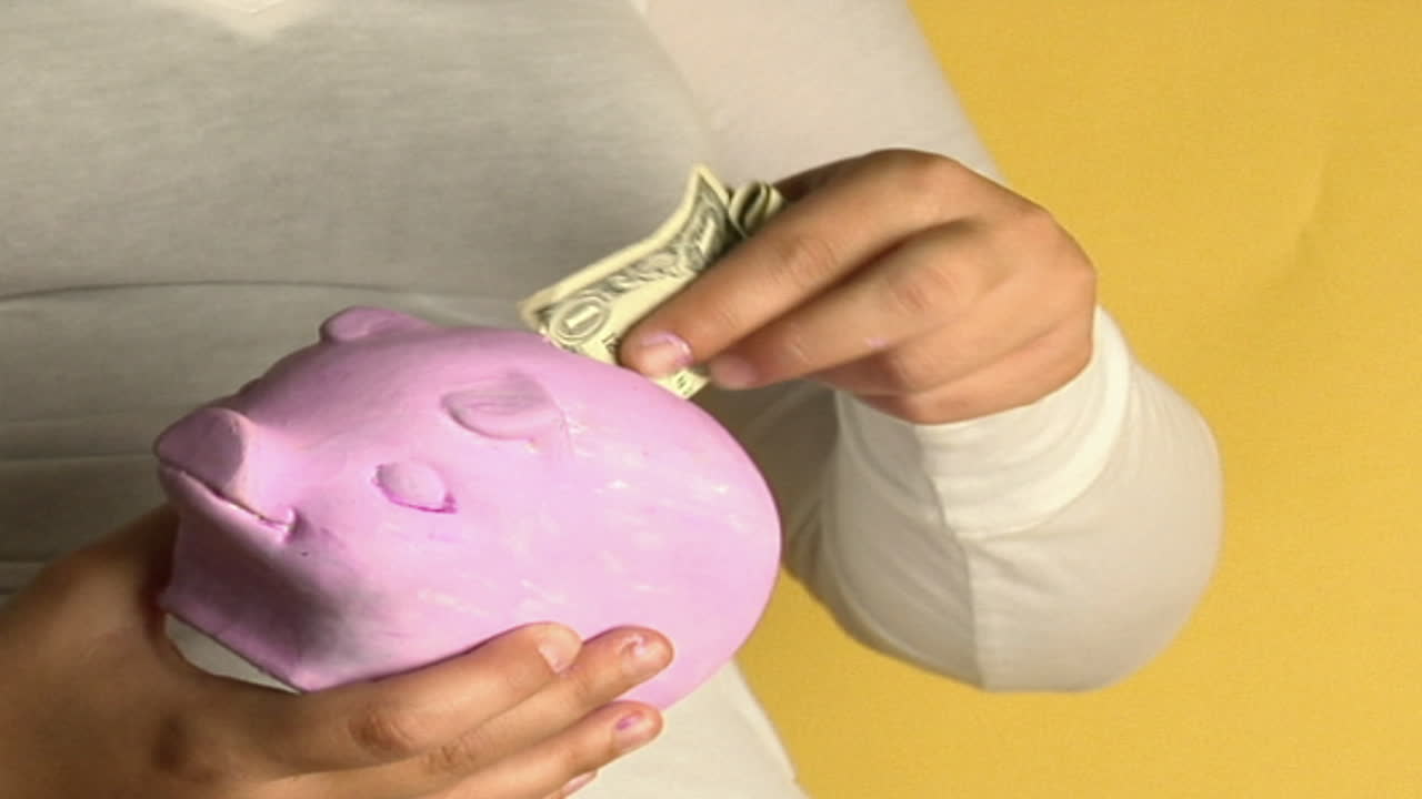 una mujer coloca monedas en una alcancía 1