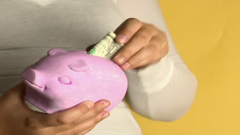 A-woman-places-coins-into-a-piggy-bank-1