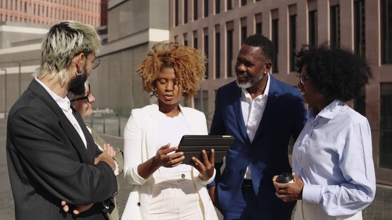 Diverse business team collaborating with a tablet outdoors