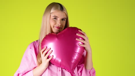 Hübsche-Blonde-Frau,-Die-Einen-Herzförmigen-Lila-Ballon-Umarmt,-Valentinsstimmung-Mit-Buntem-Hintergrund,-Studioaufnahme