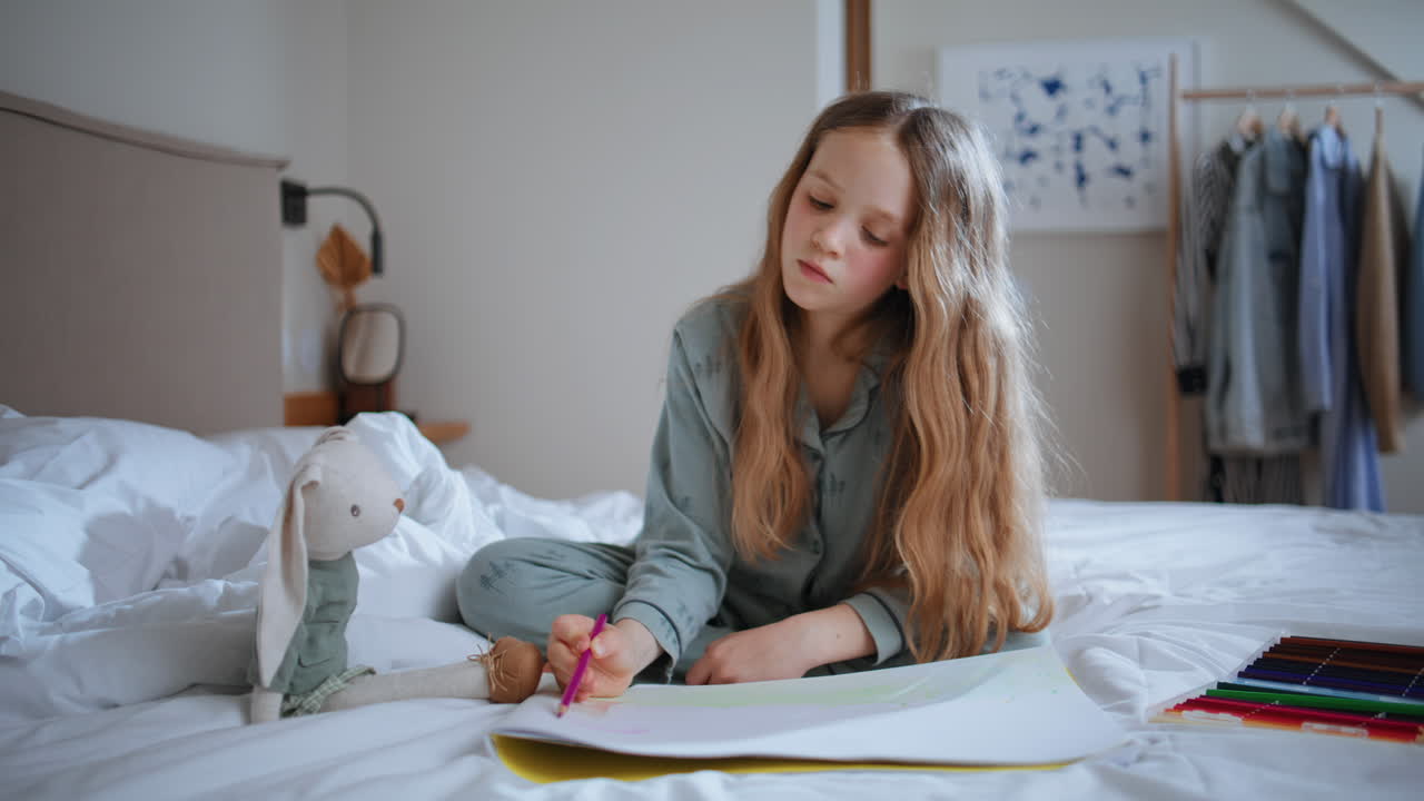 Creative kid drawing picture sitting bed at home. Little toddler painting pencil