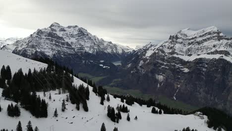 Fronalpstock-Switzerland-Glarus-Swiss-alps-sideway-slight-reveals-village-in-green-valley-below