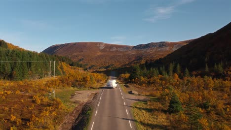 a scenic view of the road cutting through vibrant autumn foliage with a camper parked by the side