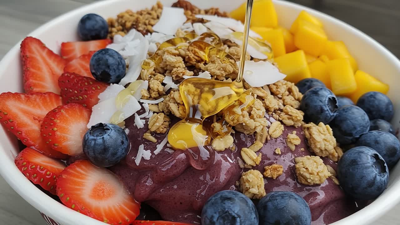 A Colorful Bowl of Deliciousness: Indulging in a Vibrant Acai Bowl Topped with Fresh Fruits, Crunchy Granola, and a Drizzle of Sweet Honey