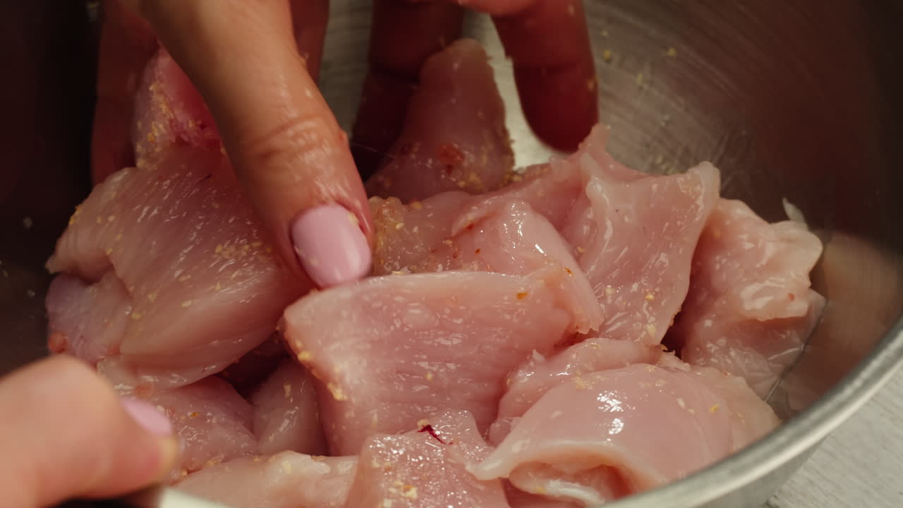 Primo piano di un uomo che affetta un filetto di tacchino o pollo crudo su un tagliere di quercia, mentre cucina con un coltello nella cucina di un ristorante. Filmato 4K di alta qualità