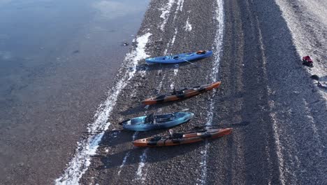 kayaks on pebble beach in iceland fjord with group of friends resting, aerial