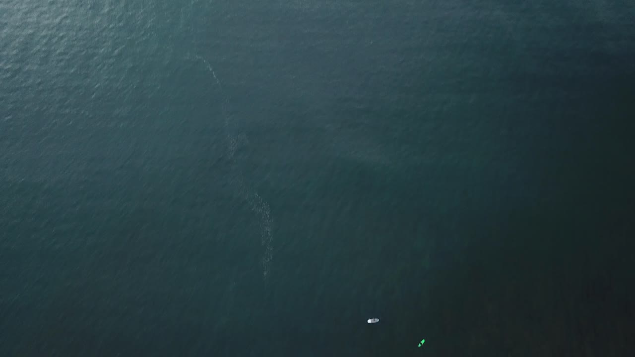 Top down drone view of paddleboarders with waves and pan up in Hanalei Bay in Kauai, Hawaii at sunset