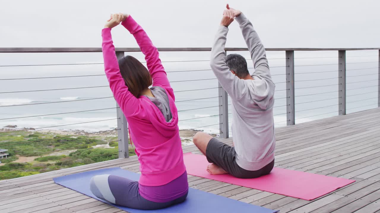 행복 한 다양한 커플 이 요가 를 하고, 발코니 에 앉아서 스트레칭 을 하고 있다