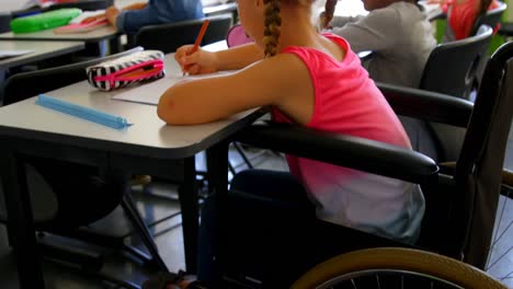 alumna caucásica discapacitada estudiando en el escritorio en el aula de la escuela 4k