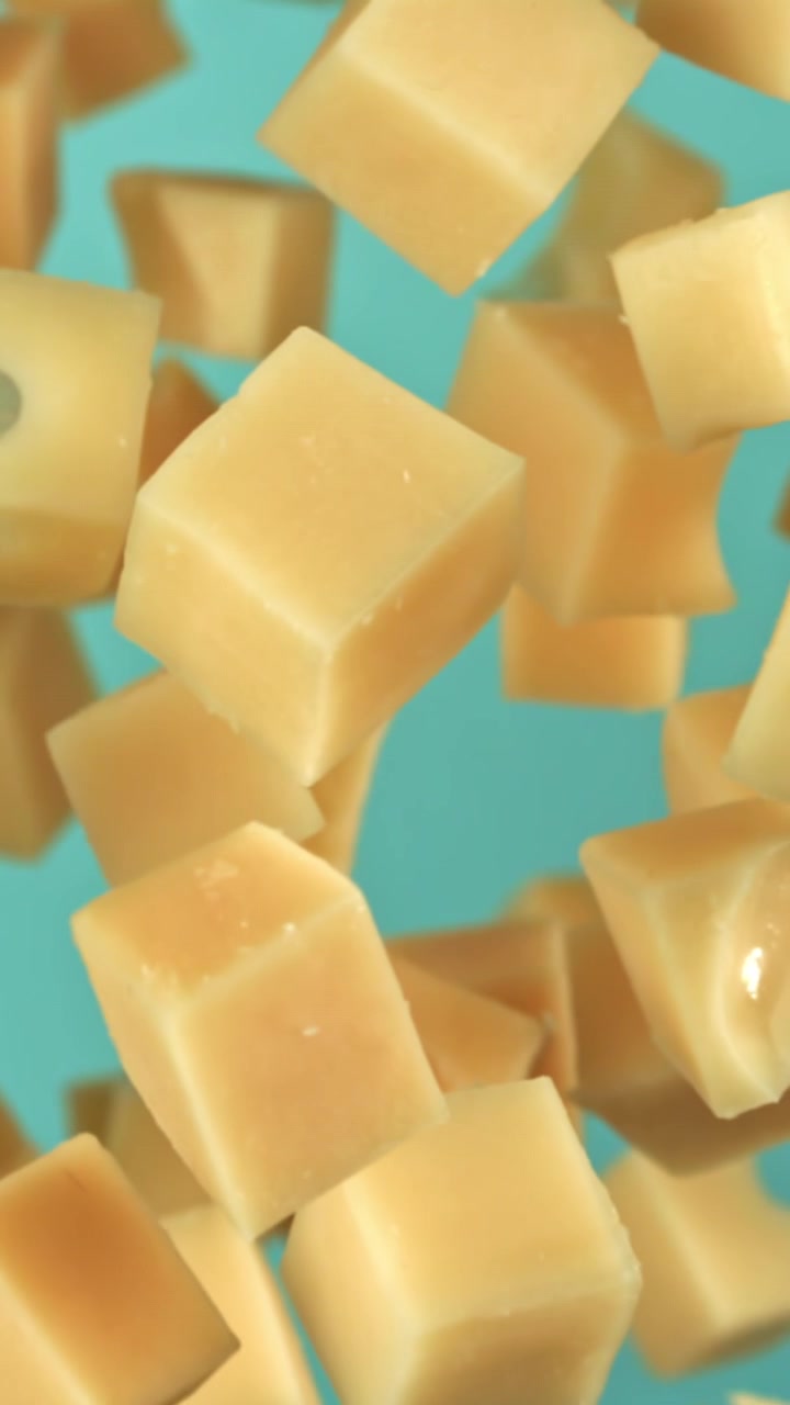 Délicieux cubes de fromage flottant au ralenti sur fond bleu