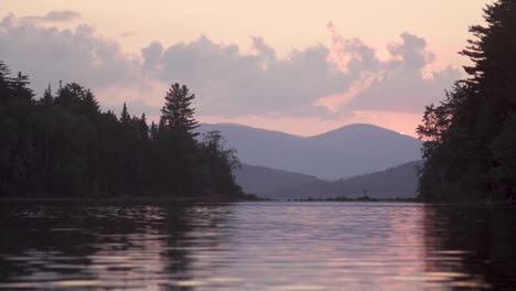 sunset over a calm lake with mountains in the background