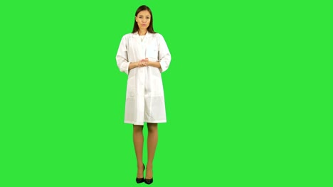 mujer joven seria en uniforme de laboratorio hablando con la cámara en una pantalla verde, clave de croma