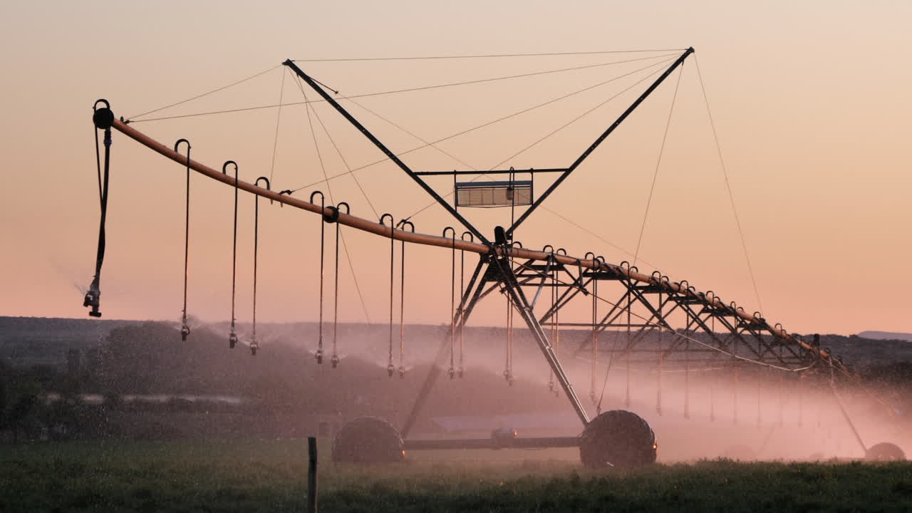 Full frame irrigation pivot sprays water on golden hour evening field