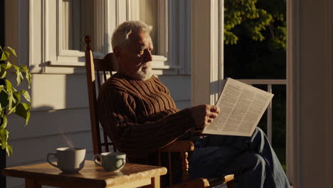 senior man reading newspaper on porch