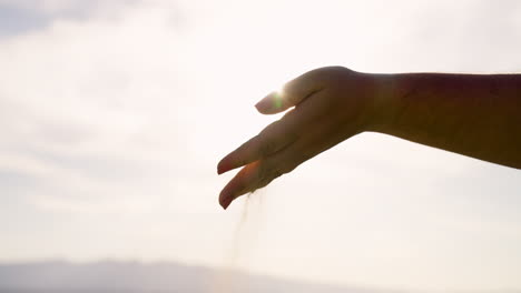 Hand-Gießt-Sand-Mit-Blendender-Sonne-Im-Hintergrund