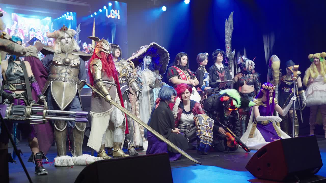 Cosplayers with all kind of different costumes on stage for an contest grouping up for photo with blue backlights having fun at a convention event at LGX Luxembourg