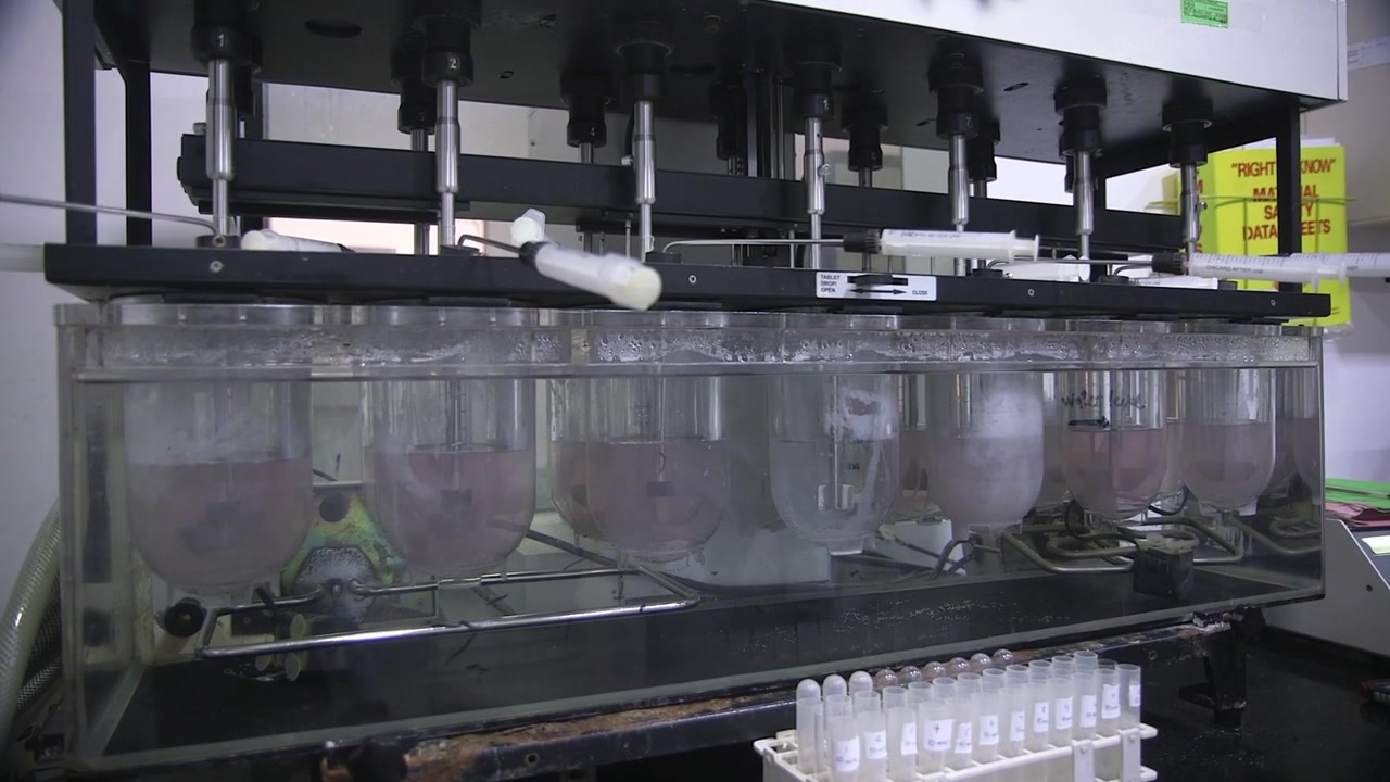 Pharmaceutical production machine operating inside a West African factory, with automated filling equipment and technician handling vials in a sterile industrial environment.